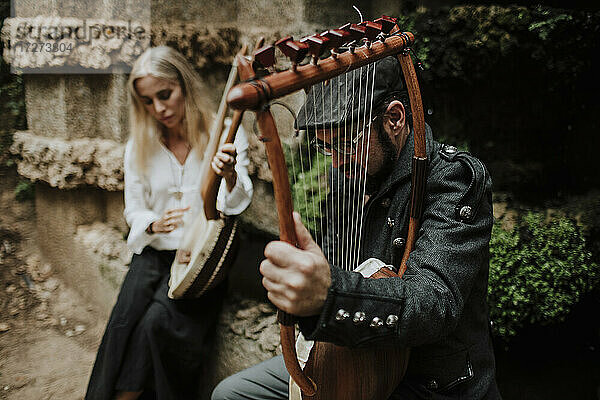 Ein Mann und eine Frau spielen ein Lyra-Instrument in einem öffentlichen Park