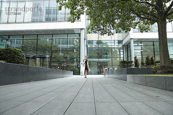 Frau geht mit Einkaufskleidung im Büropark spazieren