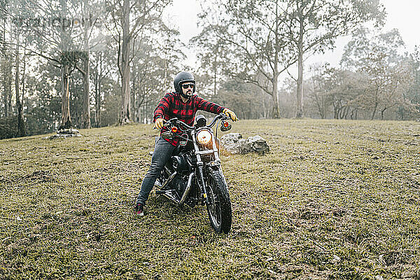Männlicher Motorradfahrer erkundet Wald bei nebligem Wetter