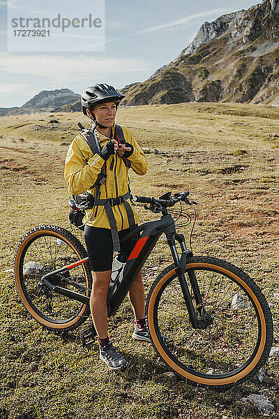 Frau in warmer Kleidung steht auf einem Mountainbike im Naturpark Somiedo  Spanien