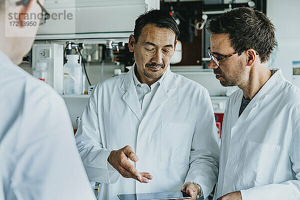Männliche Wissenschaftler benutzen ein digitales Tablet  während sie im Labor stehen