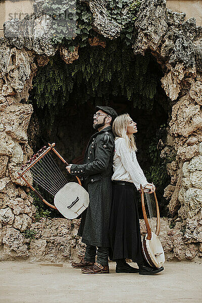 Mann und Frau mit Lyra-Musikinstrument vor gebauter Struktur