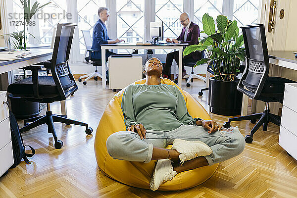 Müde Geschäftsfrau mit geschlossenen Augen auf Sitzsack im Büro ruhend