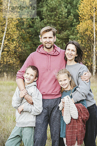 Glücklicher Mann und Frau mit Kindern auf einem Feld am Wochenende