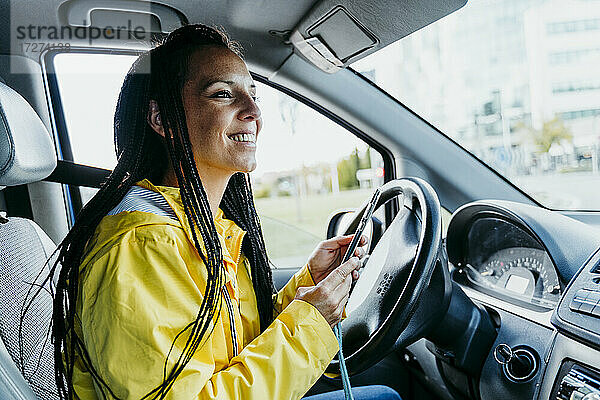 Frau benutzt Smartphone im Auto sitzend während einer Autofahrt