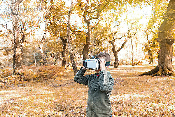 Junge trägt virtuellen Simulator  während er im Herbst im Park steht