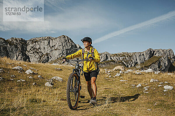 Mittlere erwachsene Frau mit Fahrrad vor einem Berg im Naturpark Somiedo  Spanien