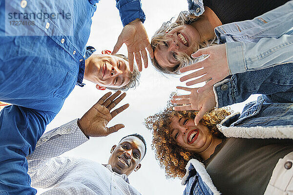 Lächelnde männliche und weibliche Freunde winken mit den Händen