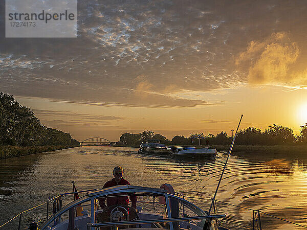 Mann  der bei Sonnenaufgang auf dem Juliana-Kanal segelt