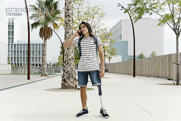 Mann mit Beinprothese spricht in der Stadt mit einem Smartphone