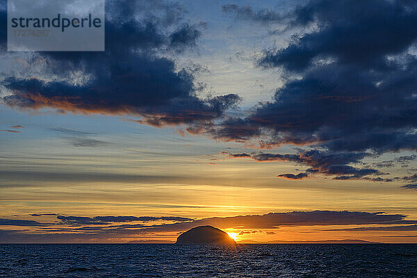 Irische See bei bewölktem Sonnenuntergang mit der Insel Ailsa Craig im Hintergrund