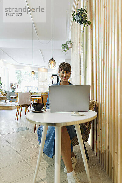 Unternehmerin mit Laptop in einem Café sitzend