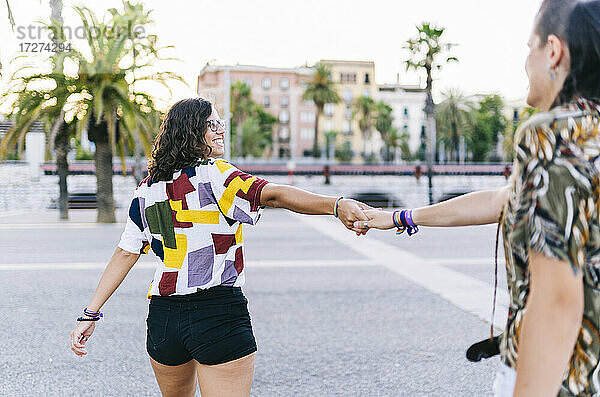 Freundinnen halten Hände  während sie auf der Straße in der Stadt stehen