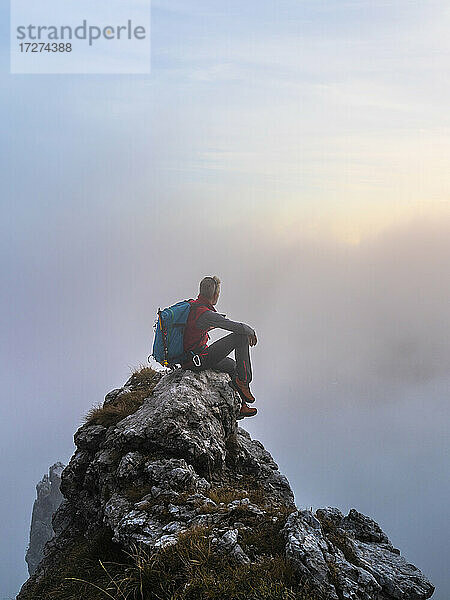 Nachdenklicher Wanderer bei Sonnenaufgang auf einem Berggipfel in den Bergamasker Alpen  Italien