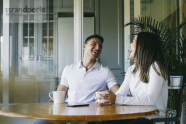 Lächelndes Paar  das zu Hause zusammen sitzt und Kaffee trinkt