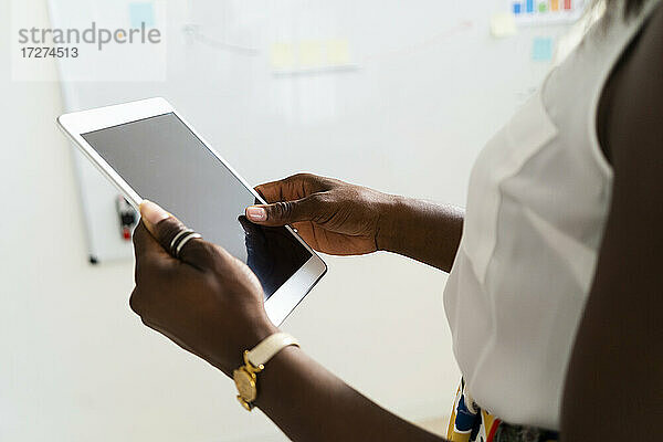 Geschäftsfrau hält digitales Tablet  während sie im Büro steht