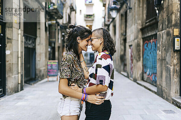Glückliches homosexuelles Paar kuschelt Nase an Nase in der Stadt stehend