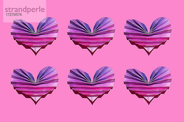 Studioaufnahme von sechs rosa und lila Origami-Herzen