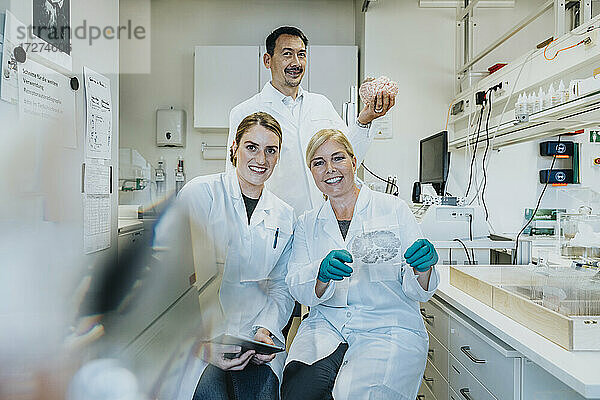 Ein Team von Wissenschaftlern hält eine Glasprobe und die Anatomie des menschlichen Gehirns im Labor