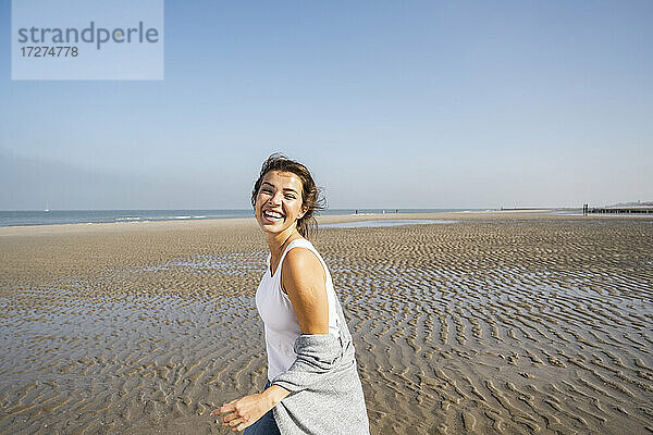 Glückliche junge Frau am Strand gegen den klaren Himmel an einem sonnigen Tag