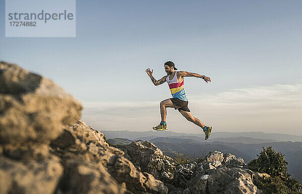 Sportler läuft auf Berg gegen klaren Himmel bei Sonnenuntergang