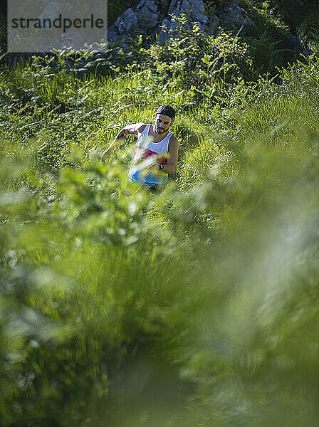 Sportler läuft zwischen Gras auf einem Berg im Wald