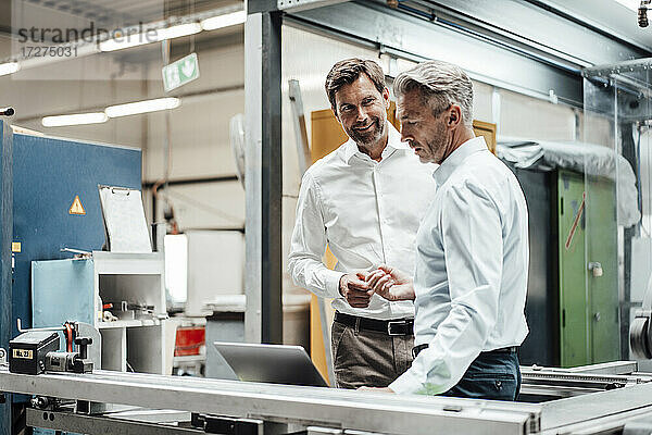 Männliche Ingenieure diskutieren in einer Fabrik über einem Laptop