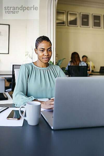 Lächelnde Geschäftsfrau bei der Arbeit am Laptop im Büro