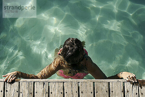 Frau genießt das Schwimmen im Pool an einem sonnigen Tag