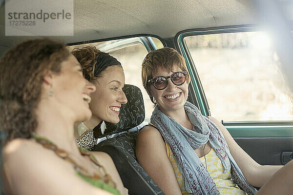 Lächelnde Freundinnen im Auto sitzend auf einer Autoreise