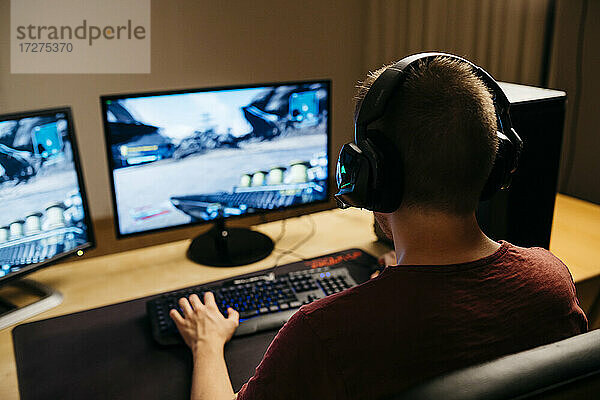 Junger Mann spielt Videospiele mit Computer am Schreibtisch