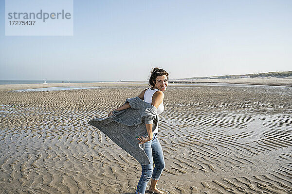 Unbekümmerte junge Frau am Strand gegen den klaren Himmel an einem sonnigen Tag