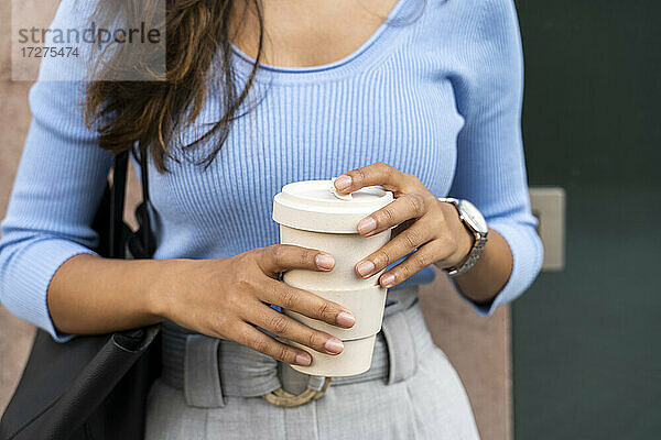 Junge Frau hält Einweg-Kaffeebecher