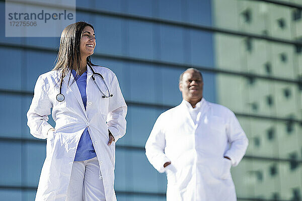 Selbstbewusste Ärzte  die mit den Händen in den Taschen vor dem Krankenhaus stehen