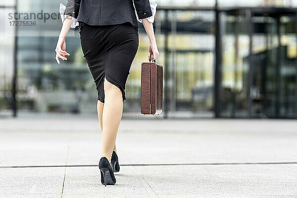 Geschäftsfrau mit hohen Absätzen und Aktentasche auf dem Fußweg