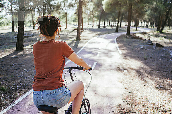 Frau fährt Fahrrad auf dem Lande an einem sonnigen Tag