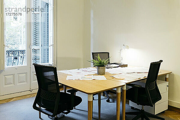 Leerer Stuhl mit Papieren über dem Tisch am Arbeitsplatz angeordnet