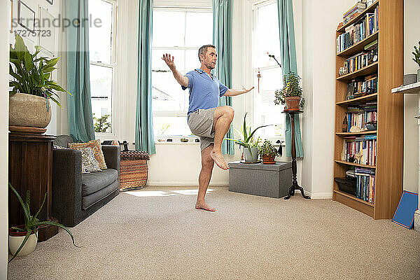 Älterer Mann balanciert auf einem Bein  während er zu Hause steht