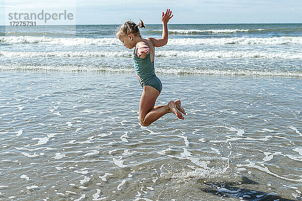 Mädchen Turner springen über Meer am Strand an einem sonnigen Tag