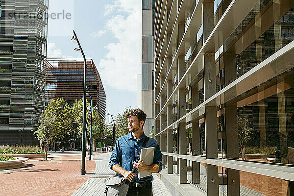 Geschäftsmann schaut weg  während er auf dem Fußweg neben einem modernen Bürogebäude geht