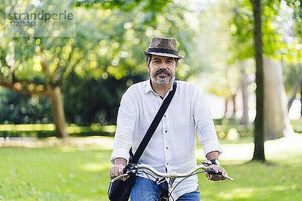Älterer Mann lächelt beim Radfahren im Park