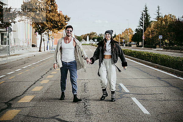 Schöne lächelnde Frau hält Hände mit männlichen Partner  während auf der Straße in der Stadt stehen