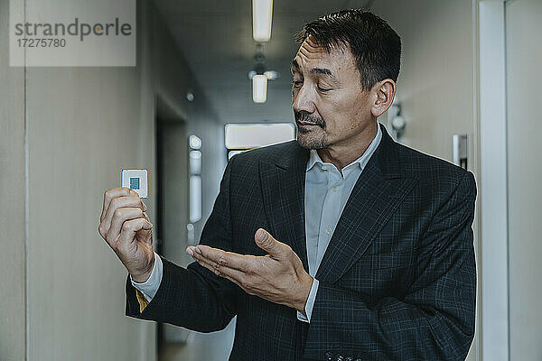 Geschäftsmann zeigt Computerchip  während er in einem Klinikflur steht