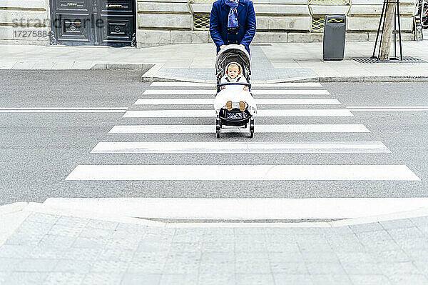 Mann mit Kinderwagen beim Überqueren der Straße in der Stadt