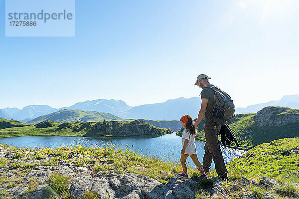 Vater und Tochter spazieren auf einer Wiese an einem sonnigen Tag