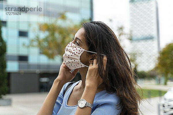 Schöne Frau mit Gesichtsschutzmaske in der Stadt während der COVID-19-Pandemie