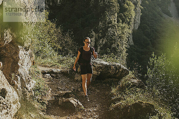 Weibliche Wanderin beim Bergabwandern an einem sonnigen Tag