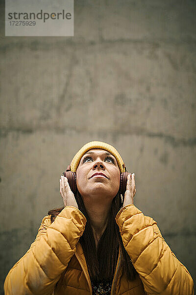 Reife Frau schaut auf  während sie über Kopfhörer Musik hört