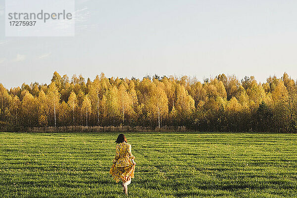 Mid erwachsene Frau zu Fuß auf Gras im Herbst Feld an einem sonnigen Tag