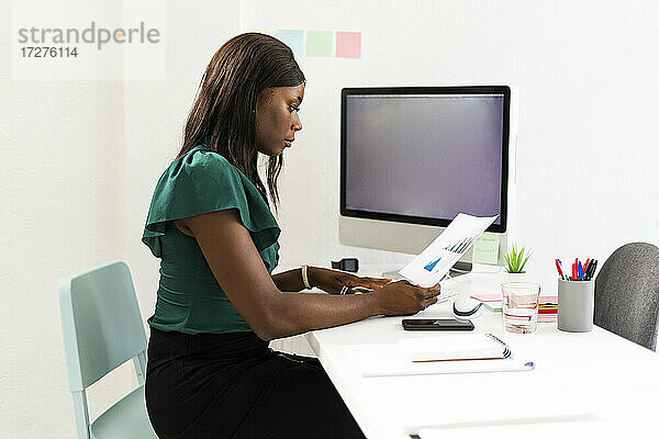 Geschäftsfrau analysiert Millimeterpapier  während sie am Schreibtisch im Büro sitzt